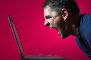 Man screaming at computer because of argument on Facebook